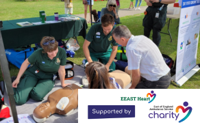 Two community first responders with a CPR mannequin talking to two members of the public.